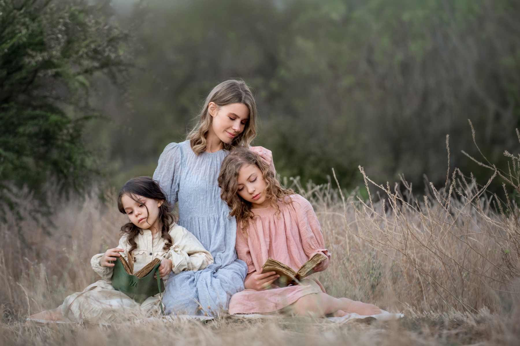 Mamá leyendo un cuento con sus dos hijas en el campo