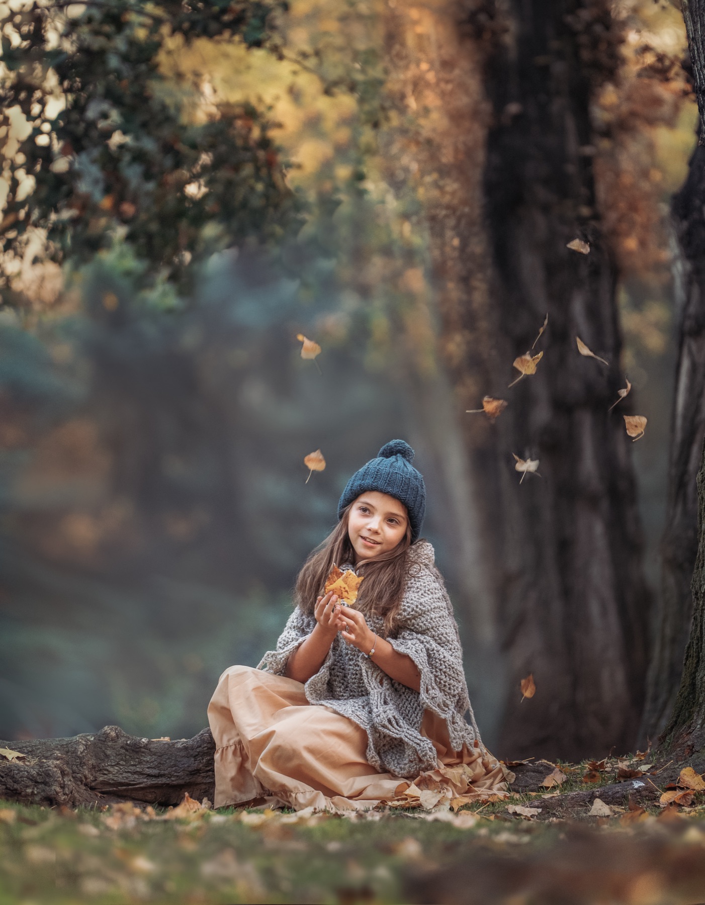 Niña sosteniendo una hoja mientras caen hojas de otoño a su alrededor